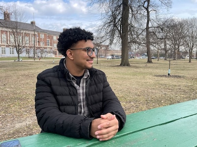 A photograph of a high school senior boy sitting at a picnic table in a park on a cloudy day.