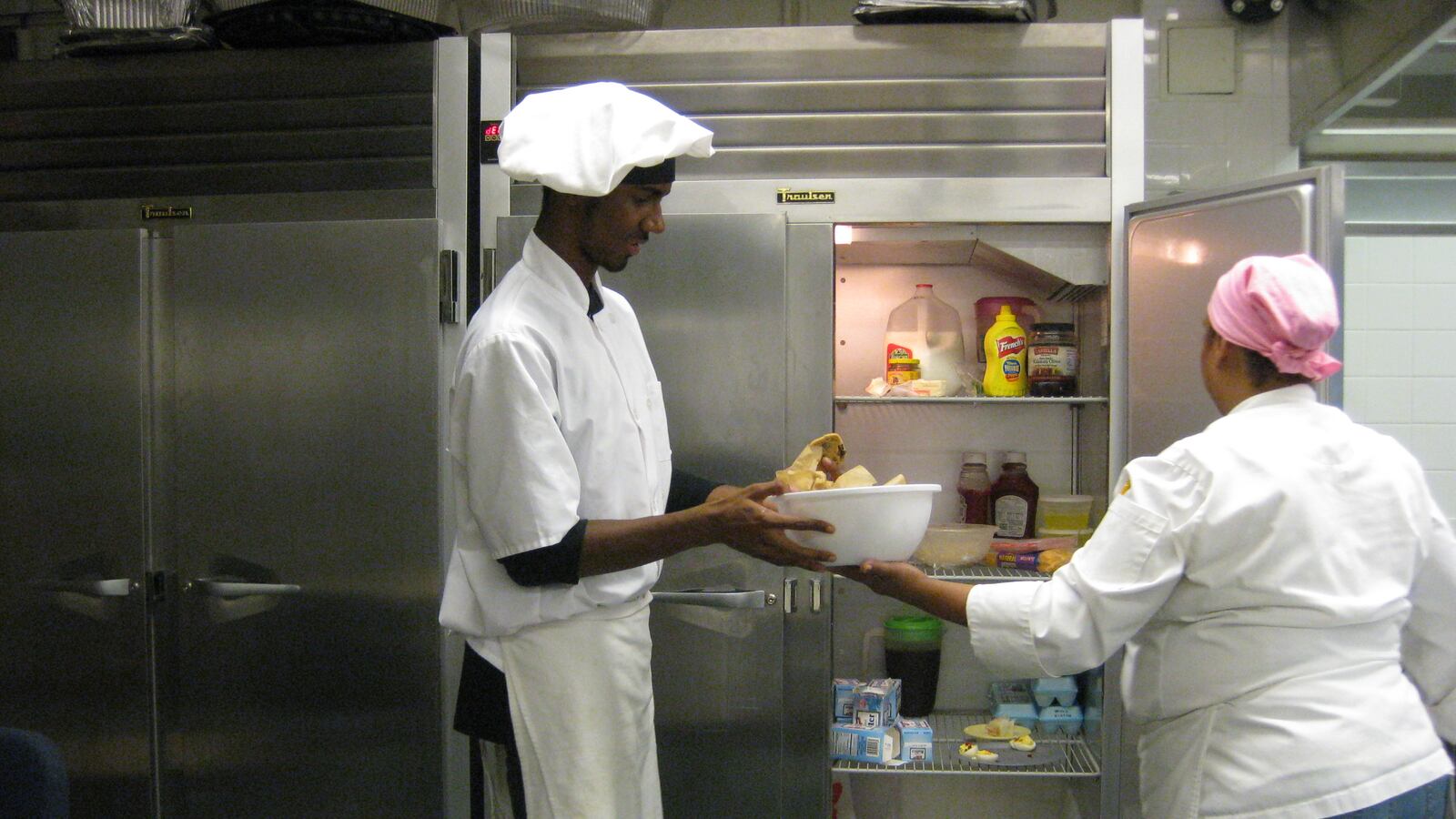 High school junior Brandon Alexander, 16, passes a mixing bowl to the Brooklyn School for International Studies culinary arts teacher Mayra Valdes.
