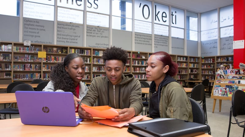 Three students sitting together at a table in a library.