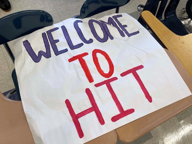 A photograph of a large piece of white paper with the words. "Welcome to HIT," in paint.