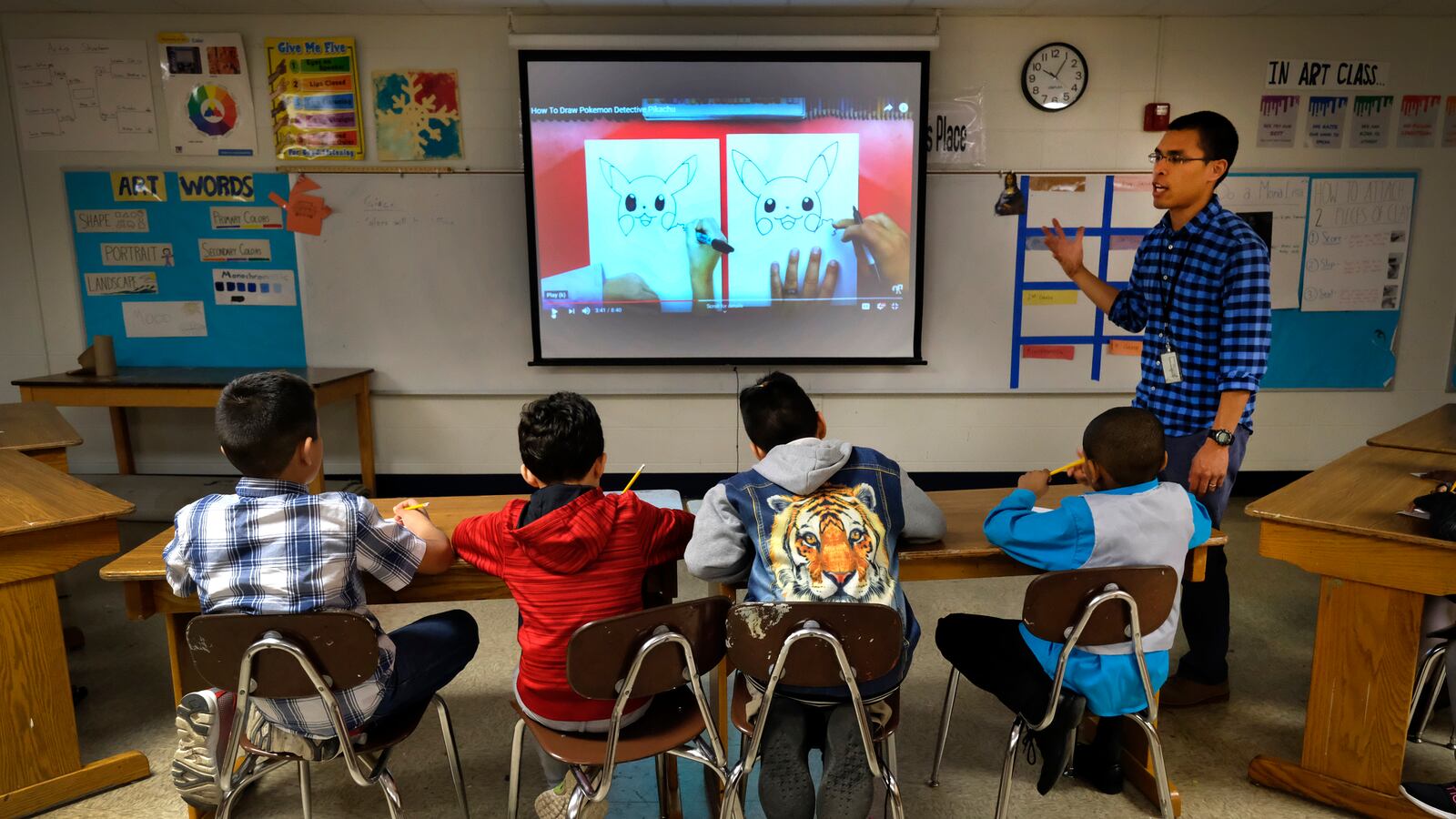 A teacher talks with students in a classroom with a smart board at Thomas Gregg Neighborhood School, an elementary school in Indianapolis, Indiana.
