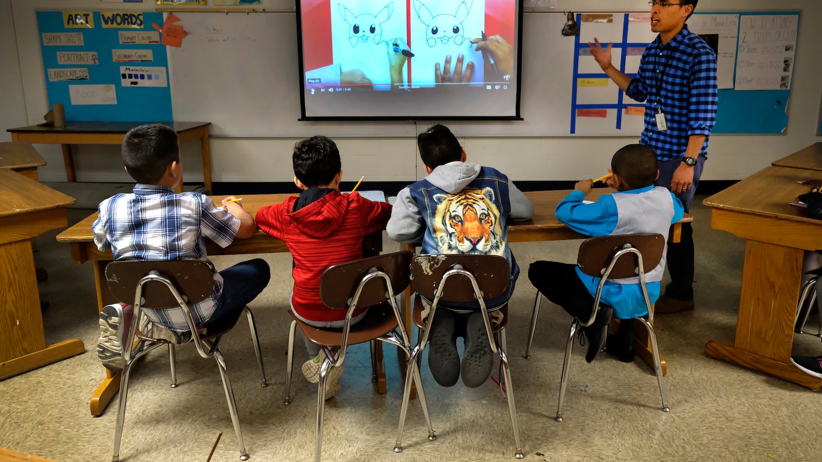 A teacher talks with students in a classroom with a smart board at Thomas Gregg Neighborhood School, an elementary school in Indianapolis, Indiana.