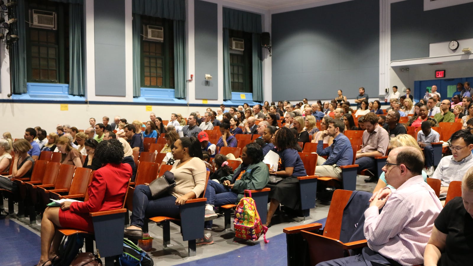 Parents fill the red chairs of a school auditorium.
