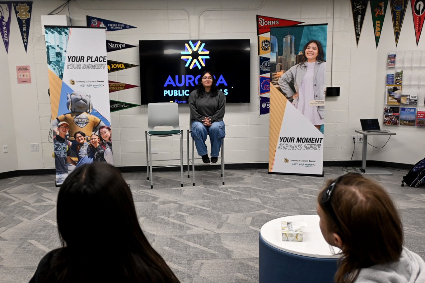 A photograph of a woman sitting in front of a group of people.