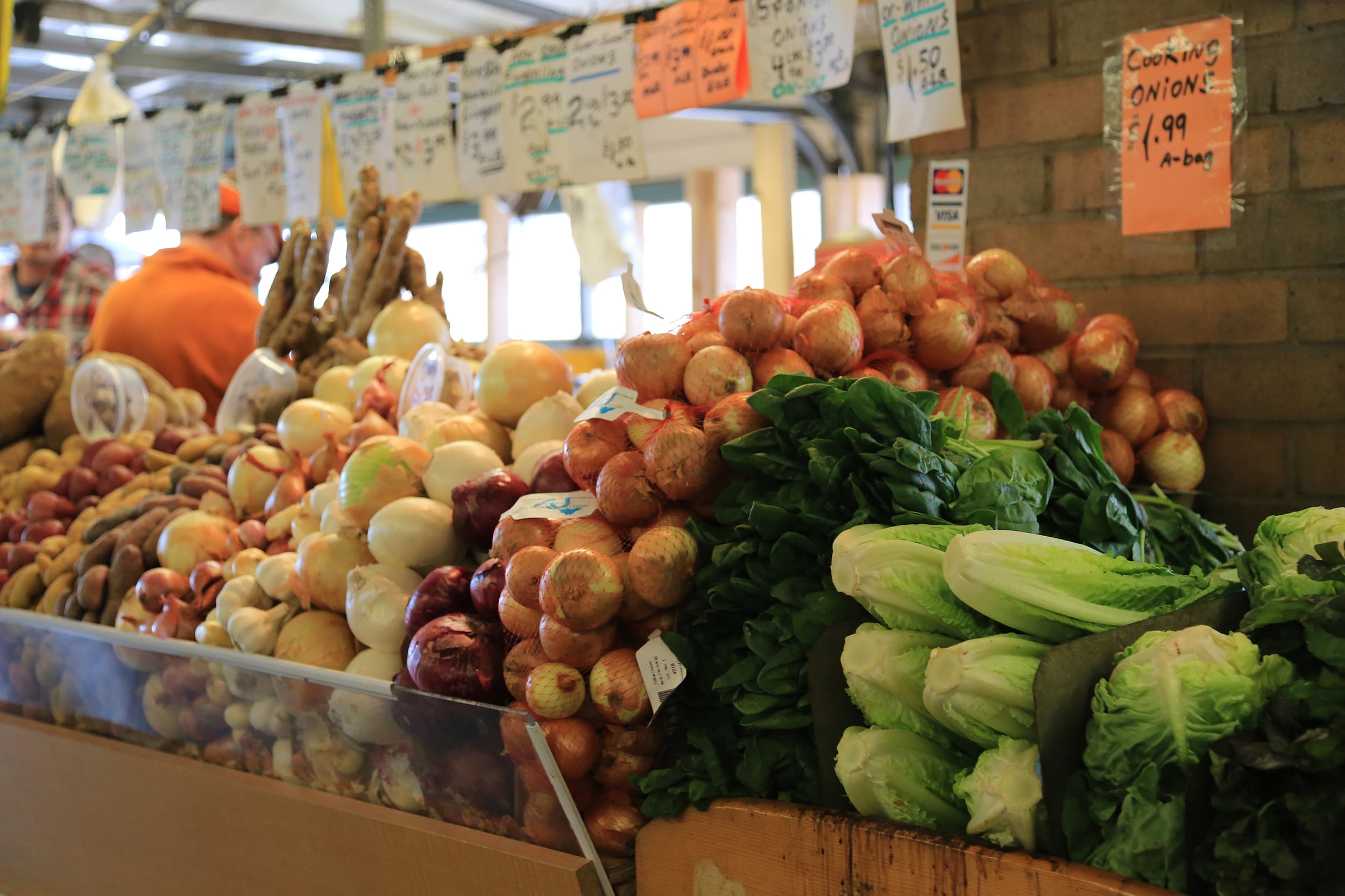 A photograph of fresh vegetables or produce on a shelf in an aisle of a grocery store.