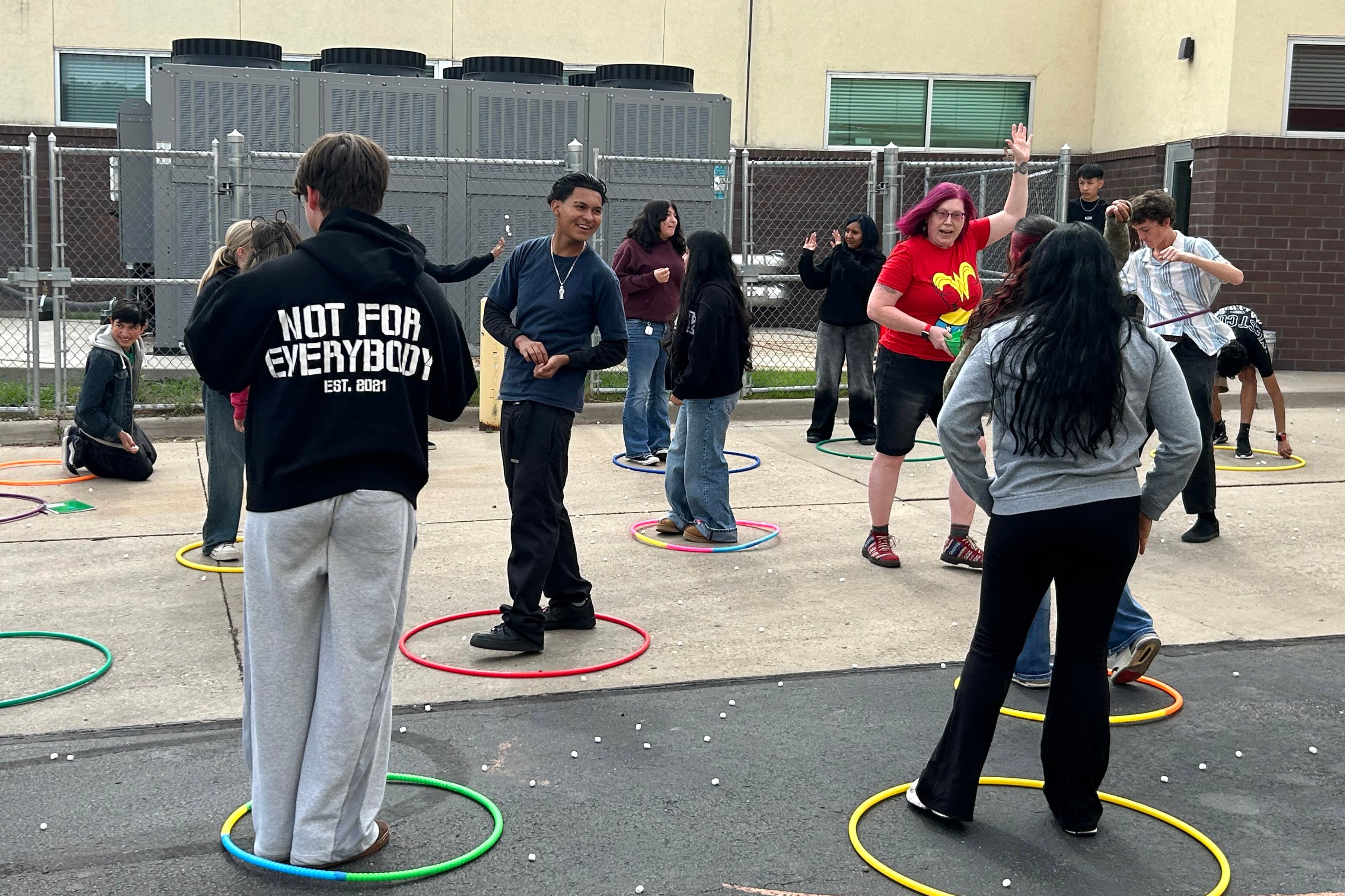 Students and a teacher do a science activity on a playground,