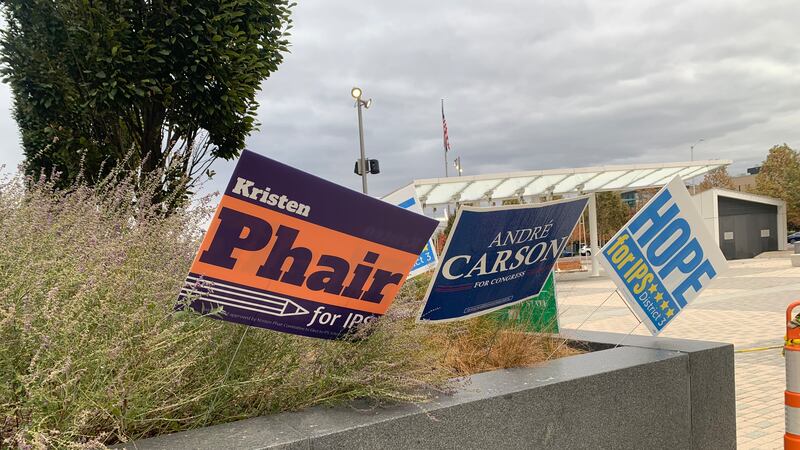 Three campaign signs for school board candidates Kristen Phair, Hope Hampton and congressional candidate Andre Carson stand in some grass.