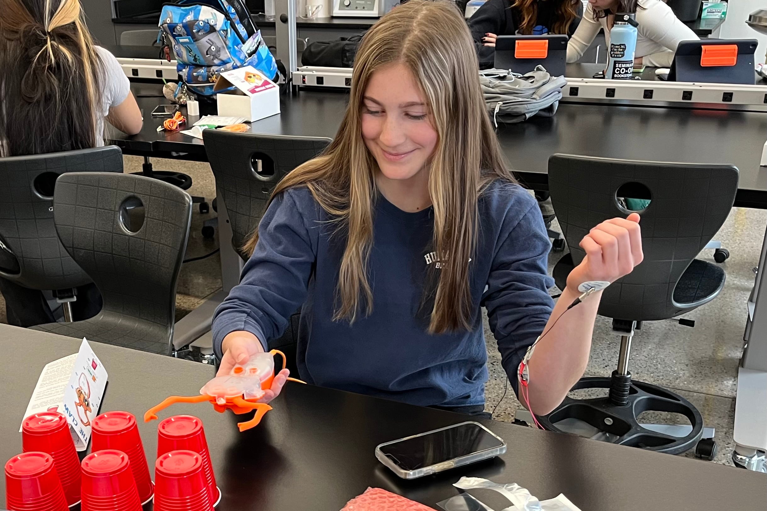 A female student in a blue sweatshirt works at a table.