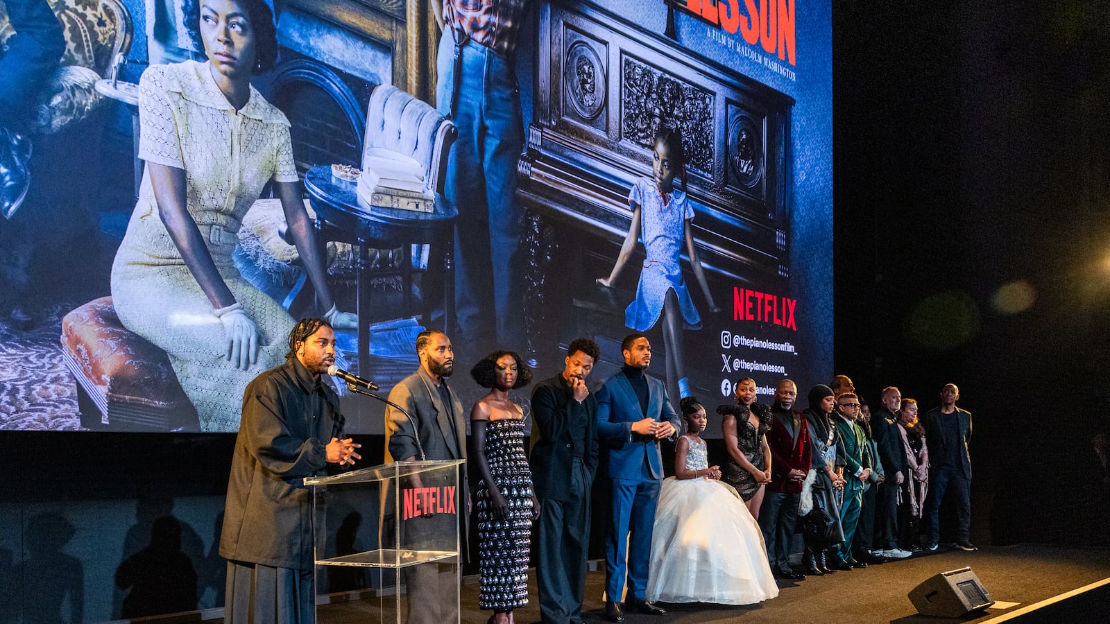 A group of people speak onstage during Netflix's "The Piano Lesson" LA premiere at The Egyptian Theatre Hollywood. Scenes from the film are behind them.