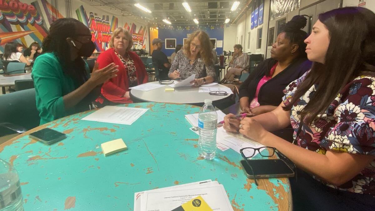 A group of people sit around a table during a meeting about literacy in Detroit.