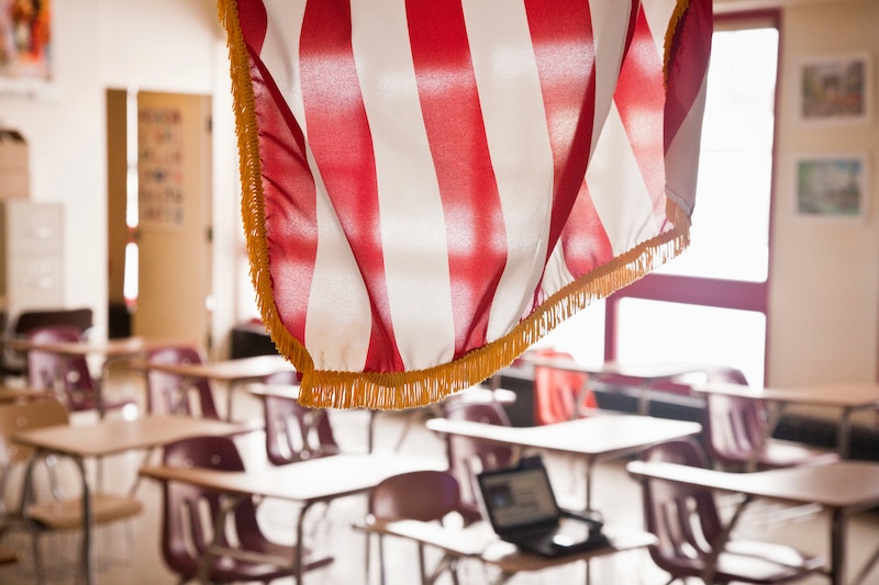 An American flag hangs in front of an empty classroom.