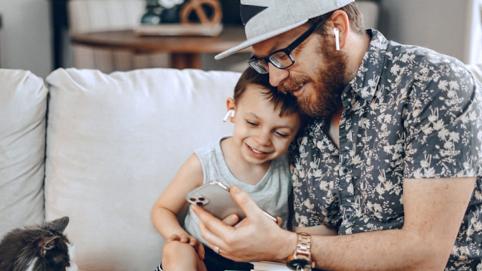 A father and child seated on a couch using the Duolingo app on his smartphone