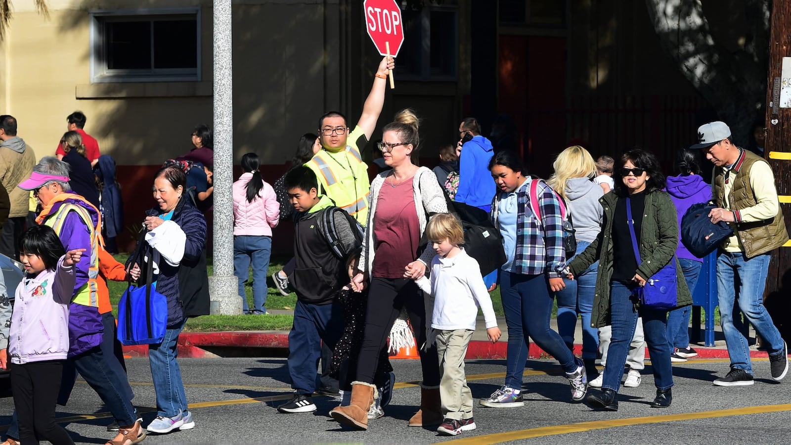 An Alhambra Unified School District crossing guard stops traffic for parents picking up their children from Ramona Elementary School on Feb. 4, 2020, in Alhambra, California. As the novel coronavirus outbreak spreads, fueling rumors and misinformation, an online petition to cancel classes in the  district had garnered more than 14,000 signatures. The petition on Change.org urges Alhambra Unified, east of Los Angeles and with a heavily Asian population, to shut down until the outbreak is over. Sc