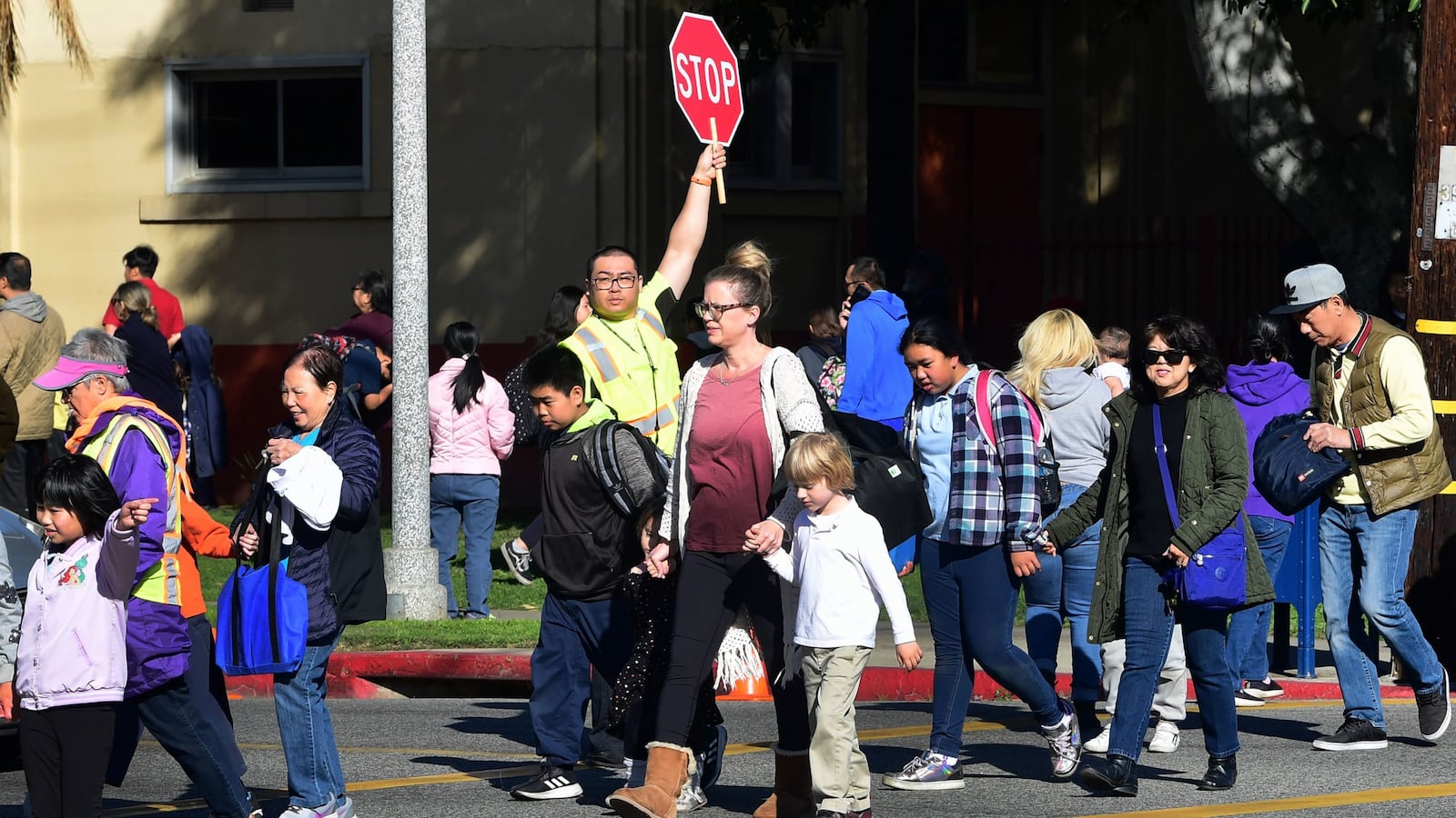 An Alhambra Unified School District crossing guard stops traffic for parents picking up their children from Ramona Elementary School on Feb. 4, 2020, in Alhambra, California. As the novel coronavirus outbreak spreads, fueling rumors and misinformation, an online petition to cancel classes in the  district had garnered more than 14,000 signatures. The petition on Change.org urges Alhambra Unified, east of Los Angeles and with a heavily Asian population, to shut down until the outbreak is over. Sc