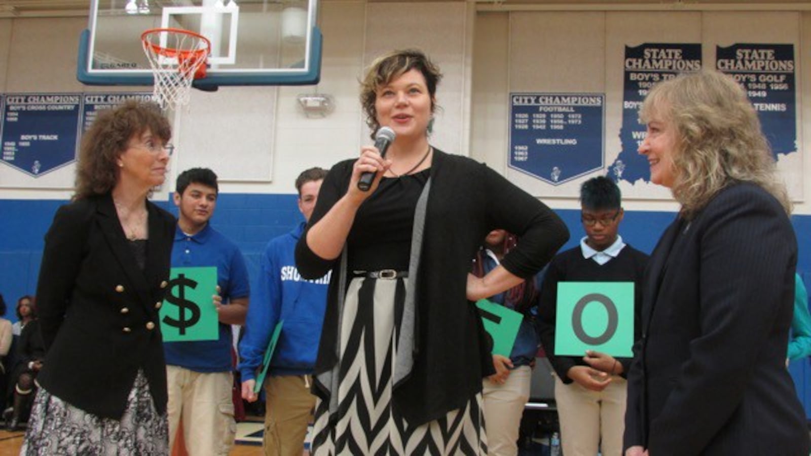 English teacher Melody Coryell speaks to Shortridge High School students after receiving the $25,000 Milken Award from Jane Foley, senior vice president of the Milken Educator Awards (left) and Indiana state Superintendent Glenda Ritz (right).