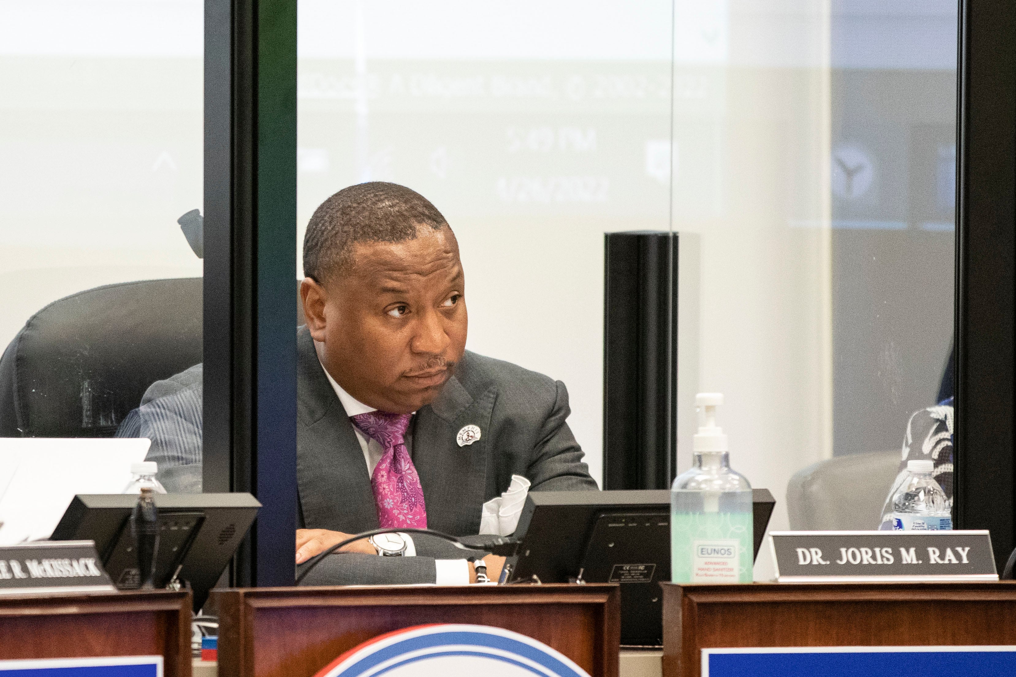 Man sits behind podium with his arms crossed