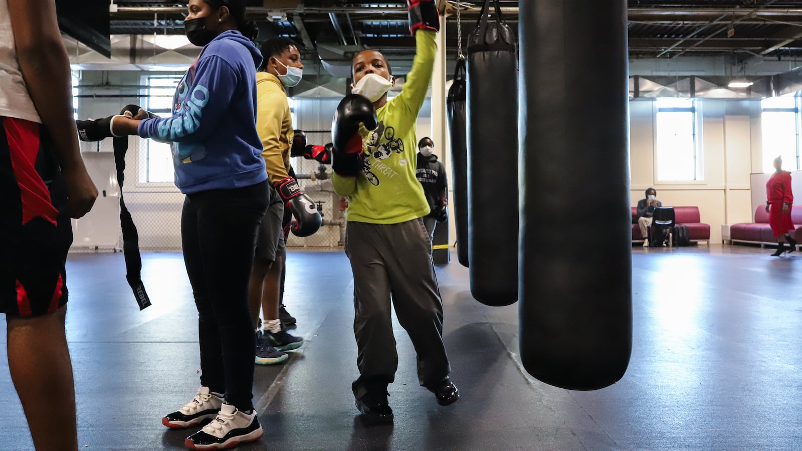 Students work on boxing and conditioning drills in a large indoor gym. 