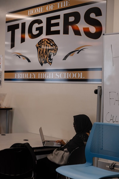 A photograph of a student sitting at a desk in a classroom.