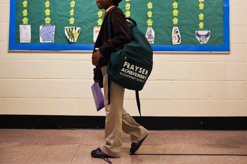 A student at Frayser Achievement Academy walks down the hallway carrying a backpack.