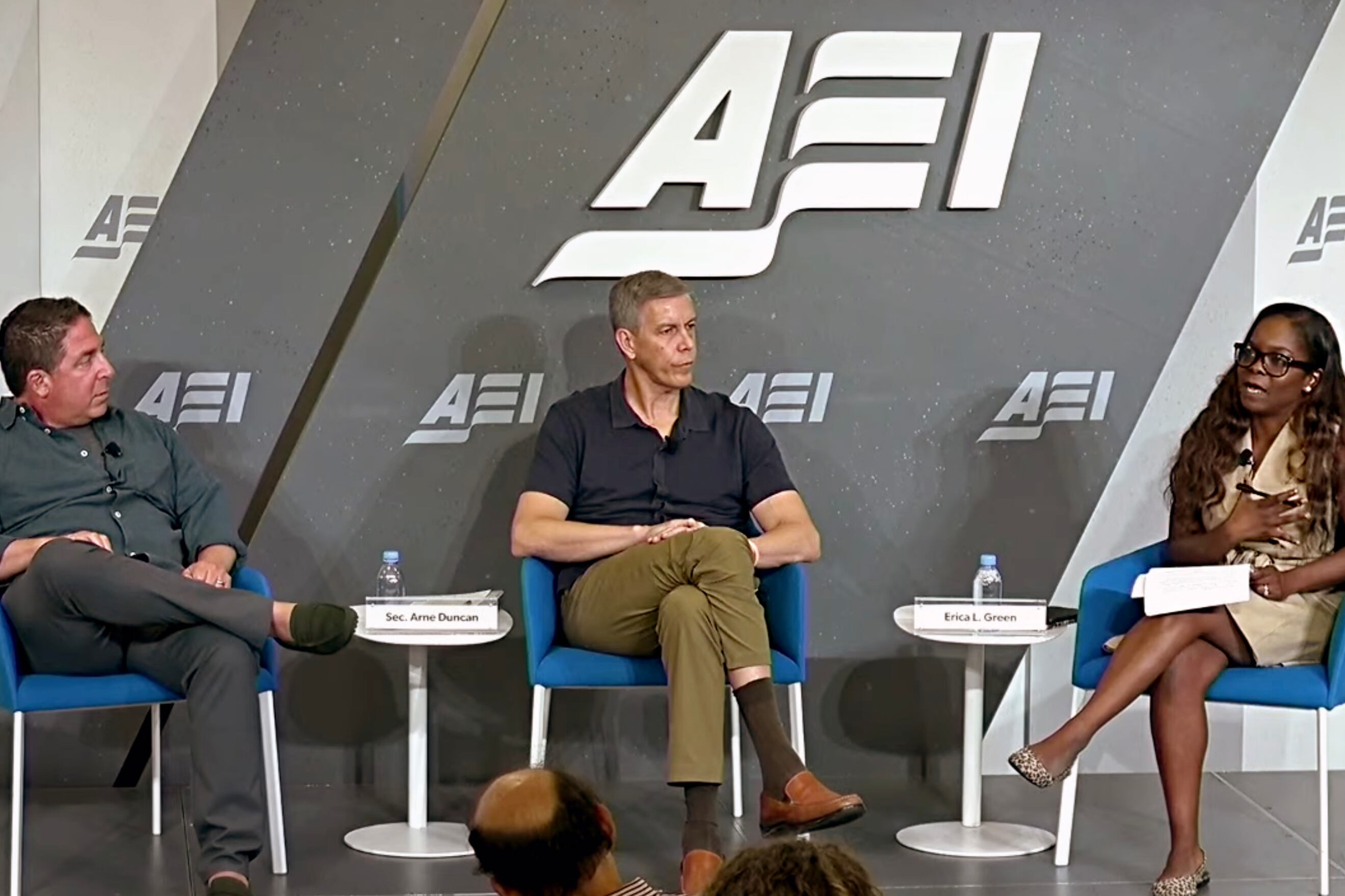 Three people sit in chairs on a stage