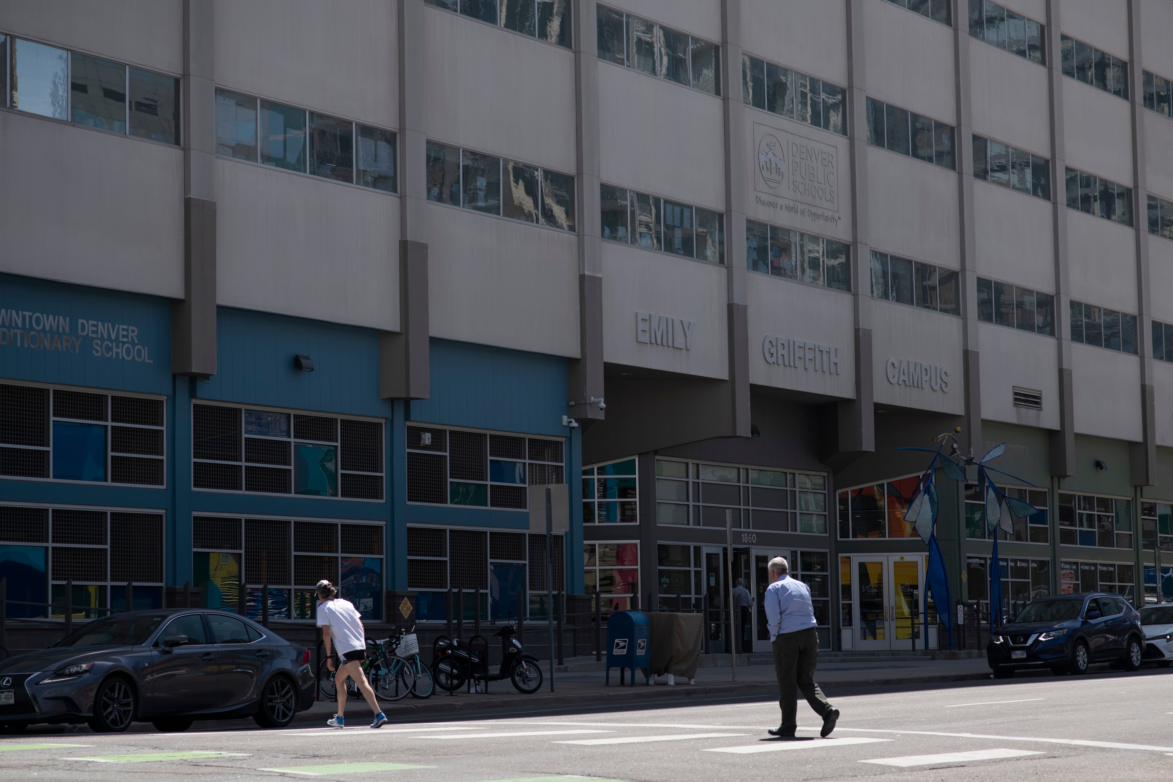 People walk across the street in downtown Denver, next to the Denver Public School’s headquarters.