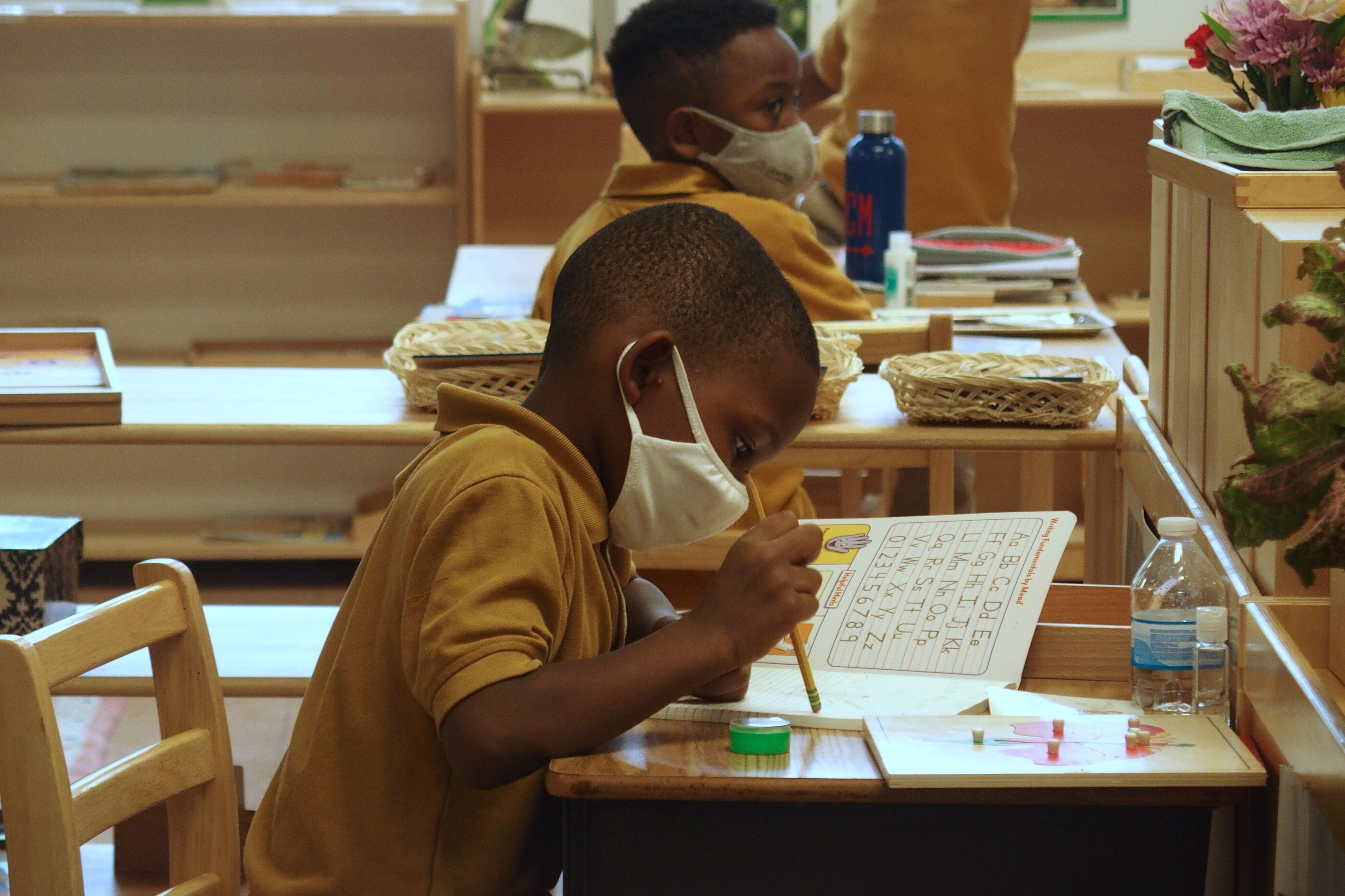 Elementary school students in masks work at their desks