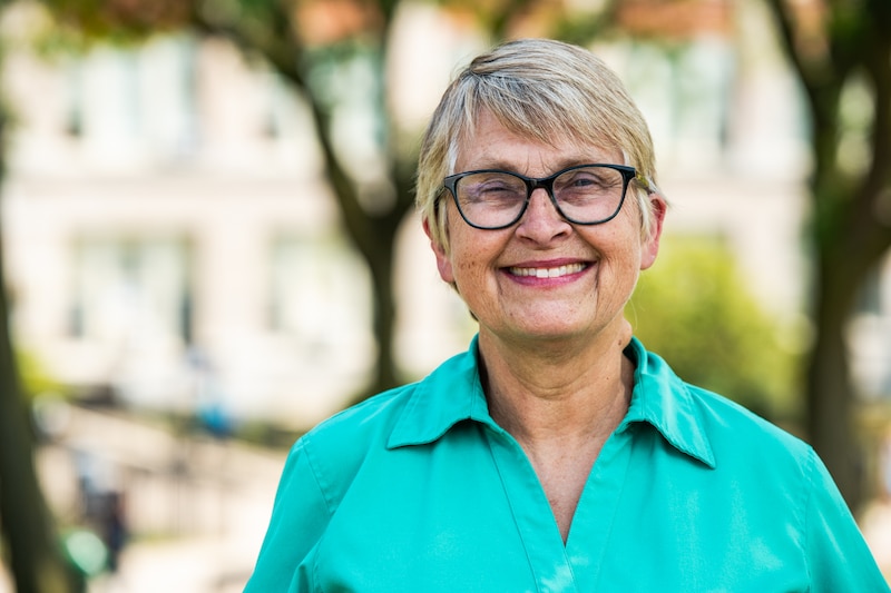 A portrait of a woman in a teal blouse.
