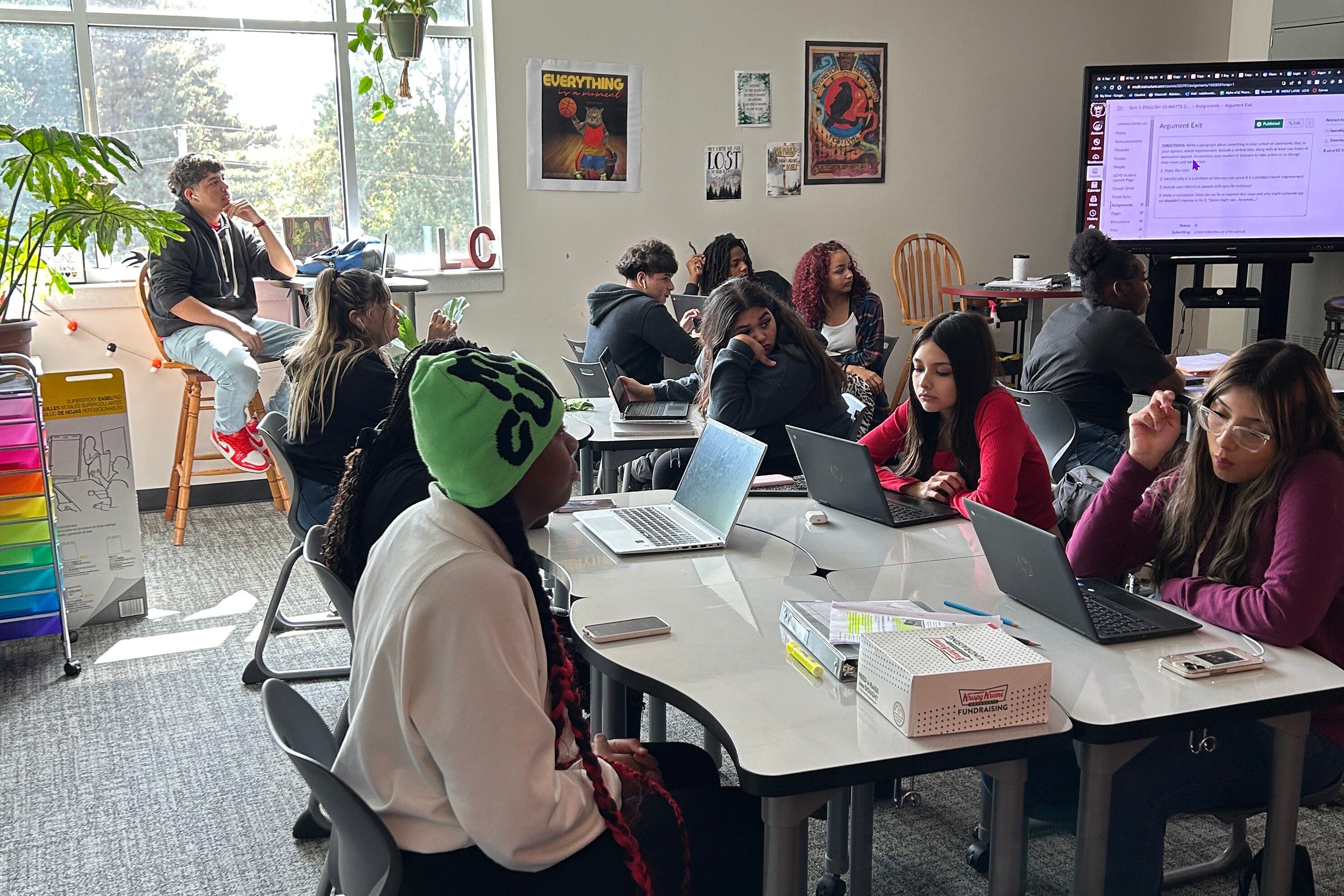 Students sit with computers at a desk.