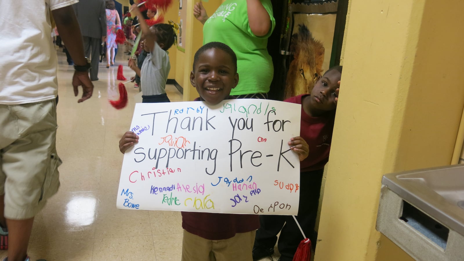 A student at Cornerstone Prep holds a sign as eventgoers move from the pep rally to an indoor town hall.