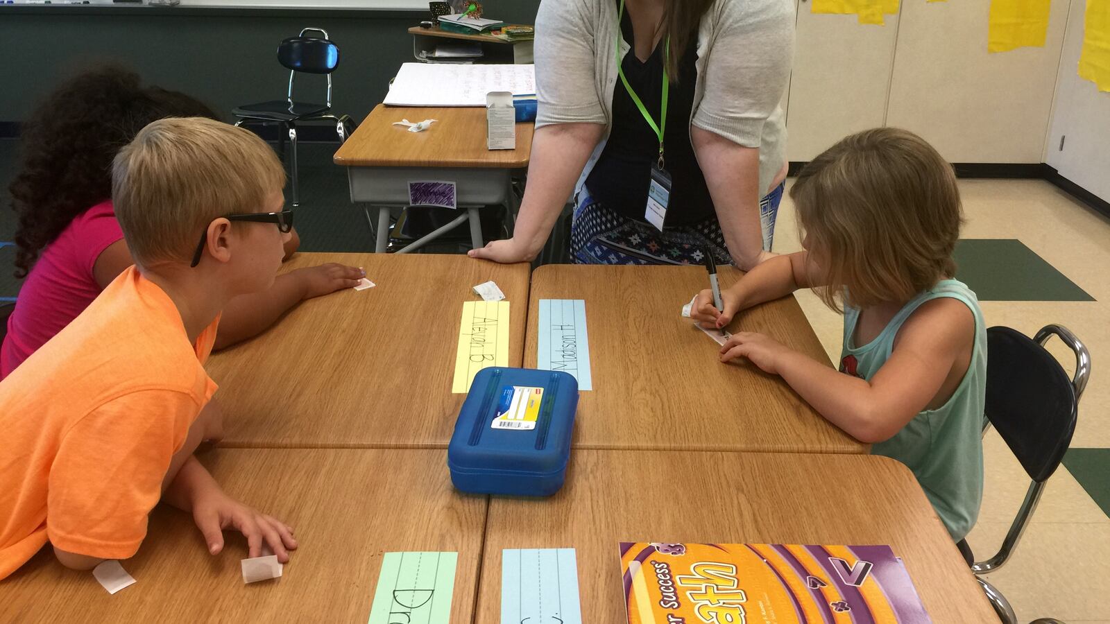 Mave Davis, a first grade teacher for Summer Advantage, looks on as a couple of students practice writing their names June 15 at Stephen Decatur Elementary School. Only 160 kids were able to participate this year, down from last year's 350.