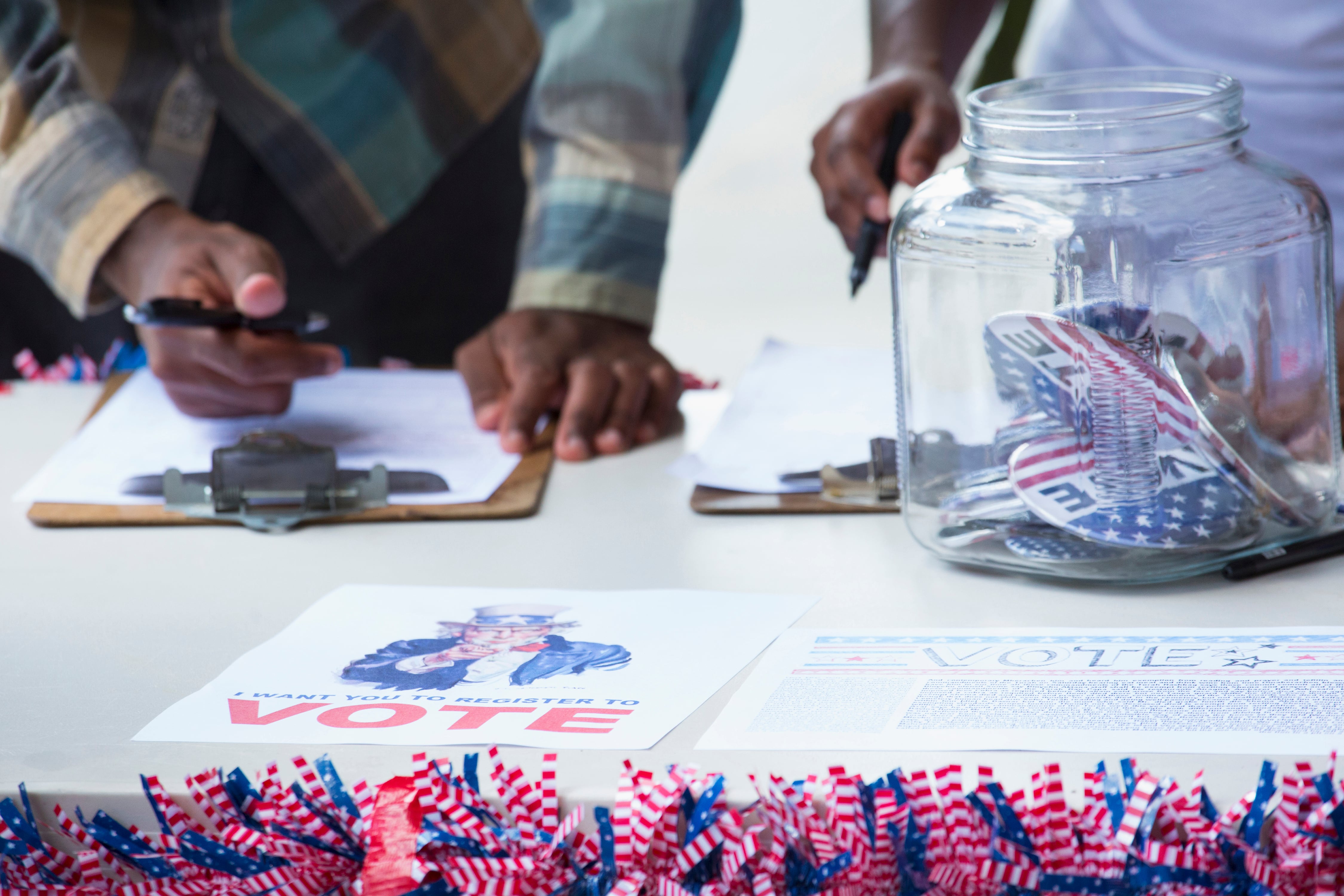 A close up of a patriotically decorated table with two sets of hands filling out paperwork.
