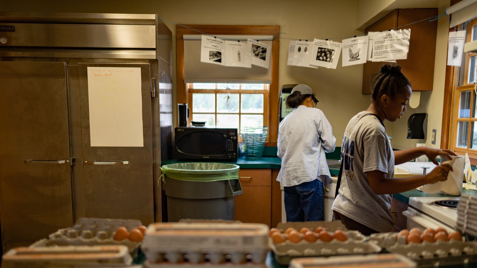 Students work on washing eggs collected on their farm in a kitchen.