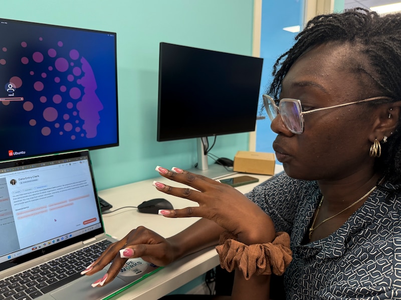 A Black female speaking while looking at a laptop in front.