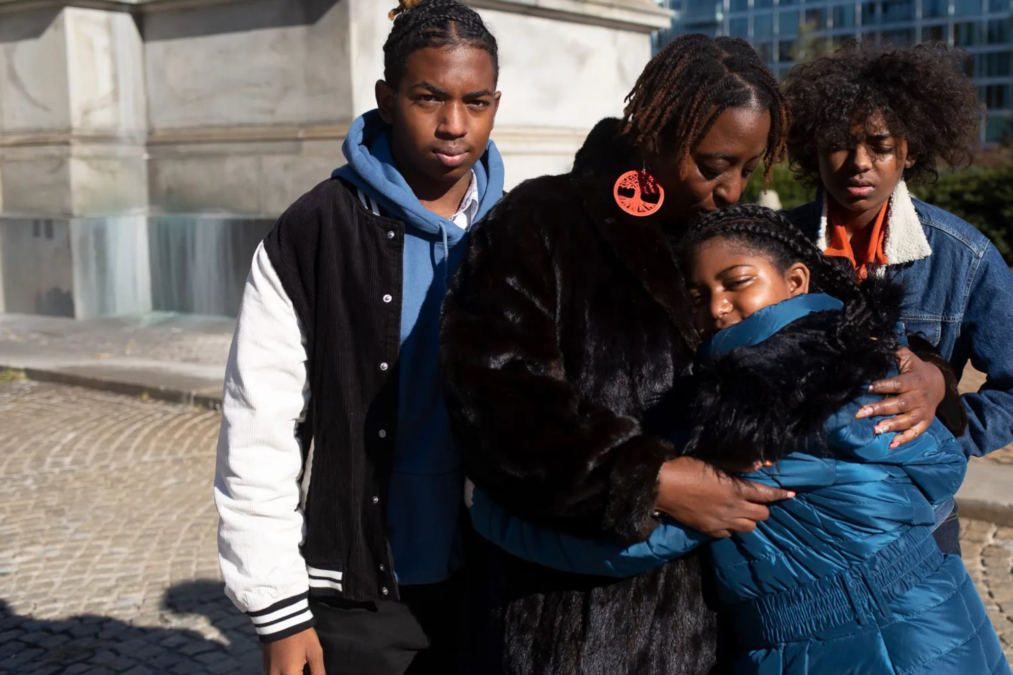 A mom embraces her daughter, while her two sons stand next to them. 
