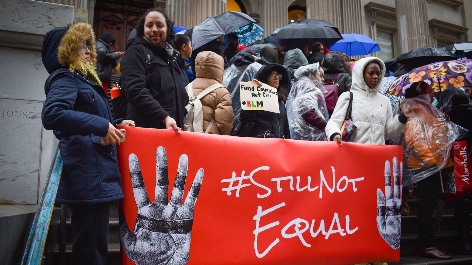 A group of people hold a red sign that says “Still Not Equal.”