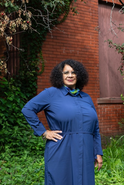 A woman wearing a dark blue dress poses for a portrait outside.