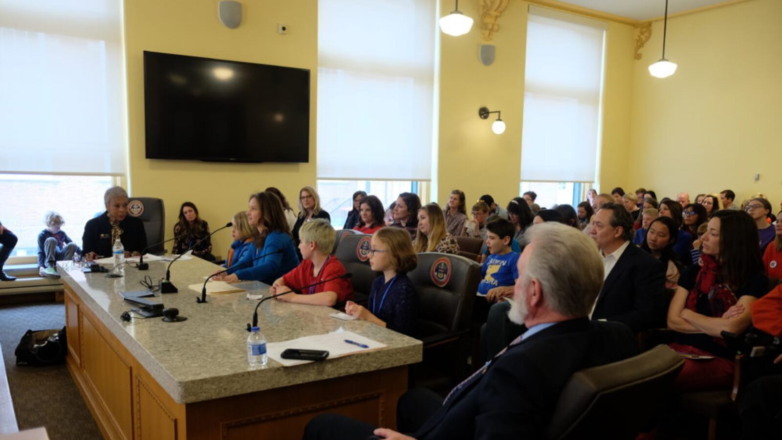 Mindy Russell, a teacher at Vertical Skills Academy, testifies on behalf of dyslexia legislation with her students, as bill sponsors Janet Buckner and Jim Wilson look on.