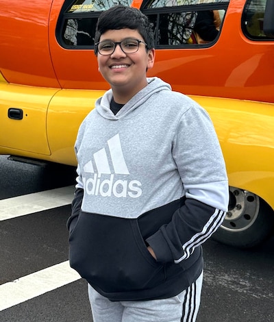 A teenage boy with glasses and a gray and black sweatshirt