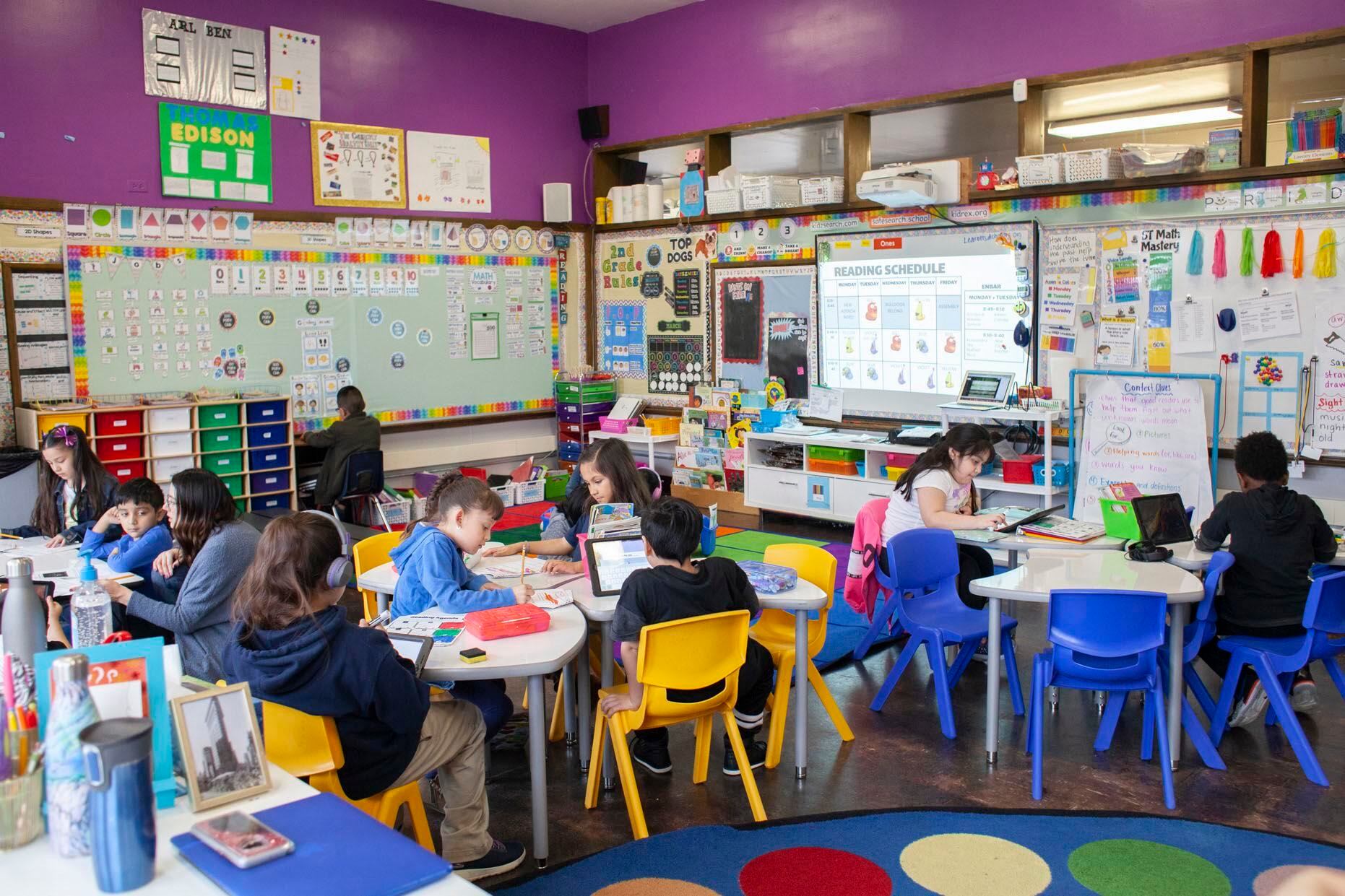 Students at CICS West Belden sit at white table with yellow and blue chairs to do school work in classroom at the Chicago charter school. The school employs the personalized learning method for its K-8 students.