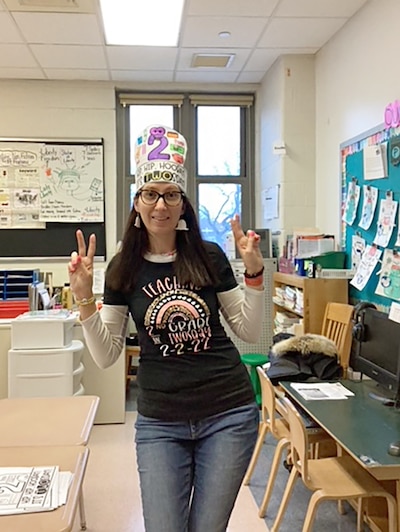 An adult teacher poses for a portrait in a classroom.