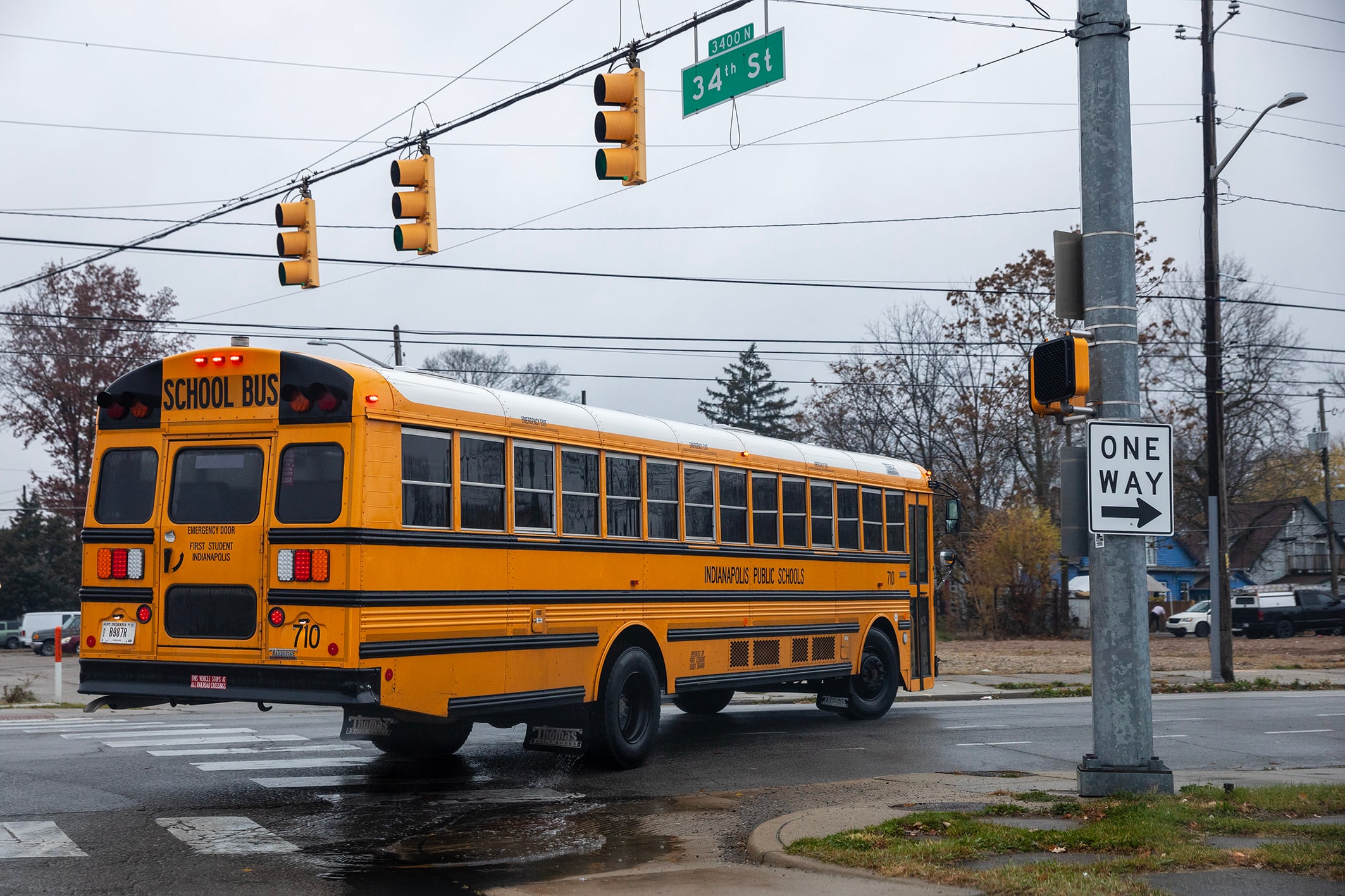 A large yellow and black school bus turns a corner on a street under a street light.
