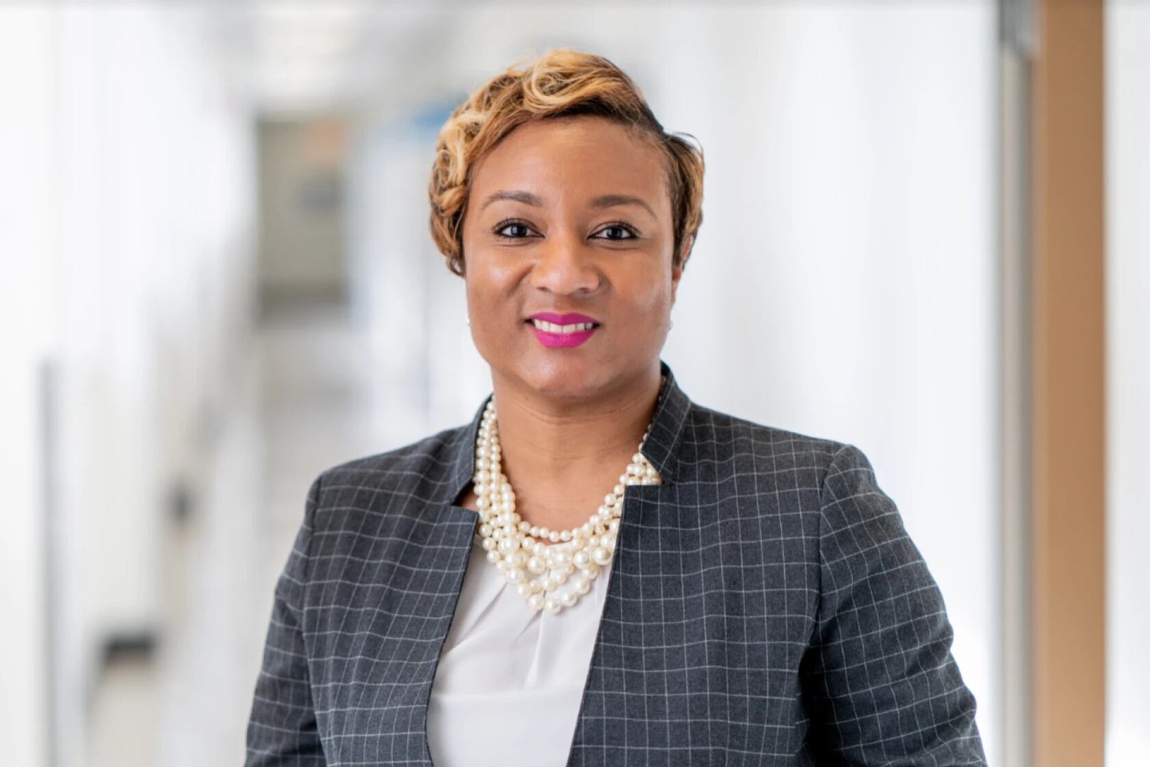 Photo of woman with short light hair and wearing a dark suit facing straight ahead smiling for a portrait.