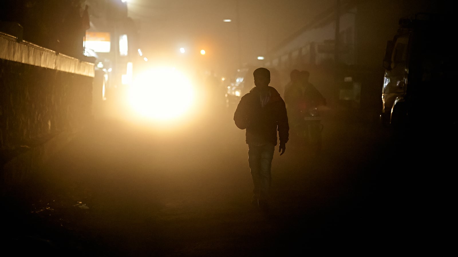 A boy walks outdoors in the dark.