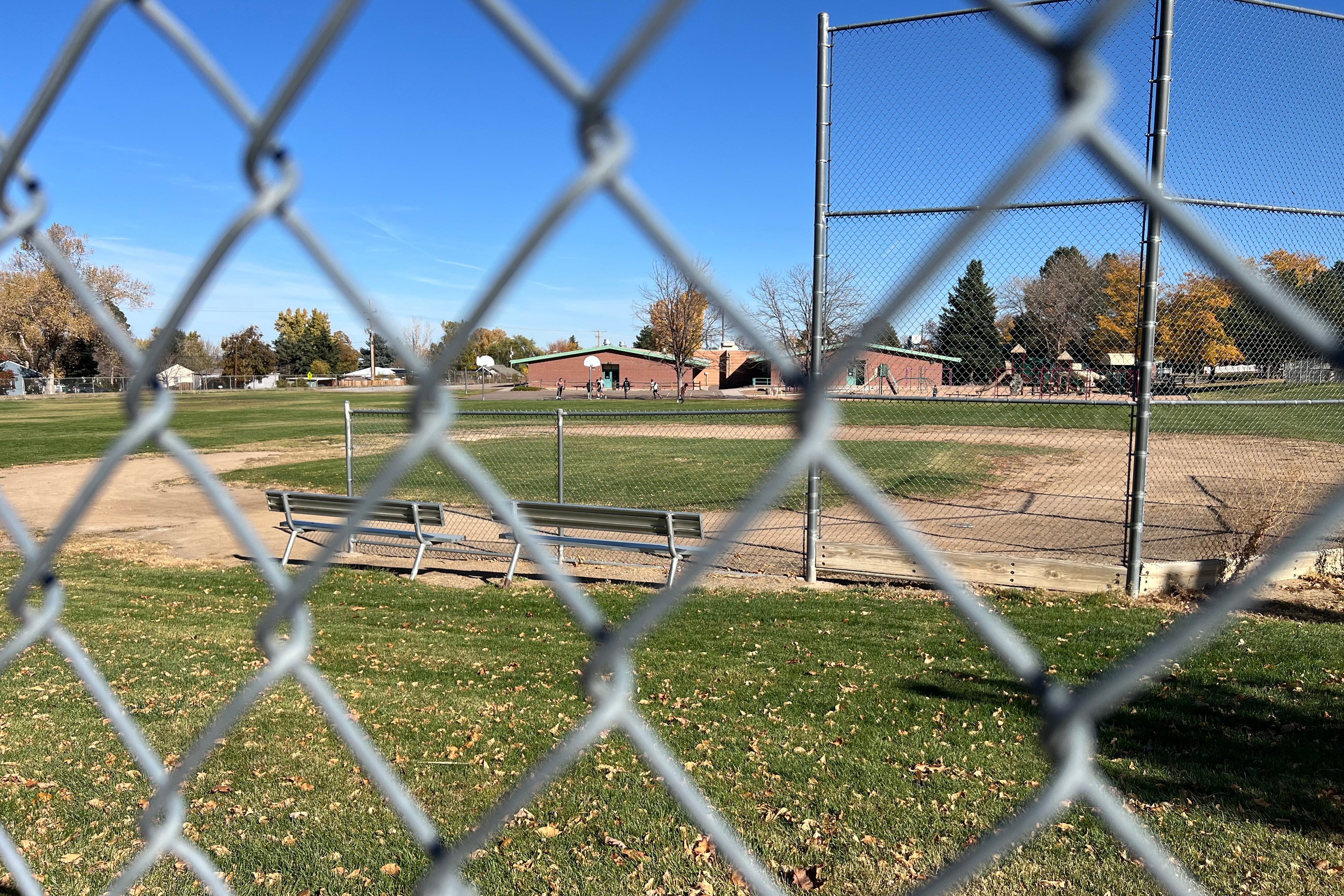 A photograph of an empty baseball field next to a school.