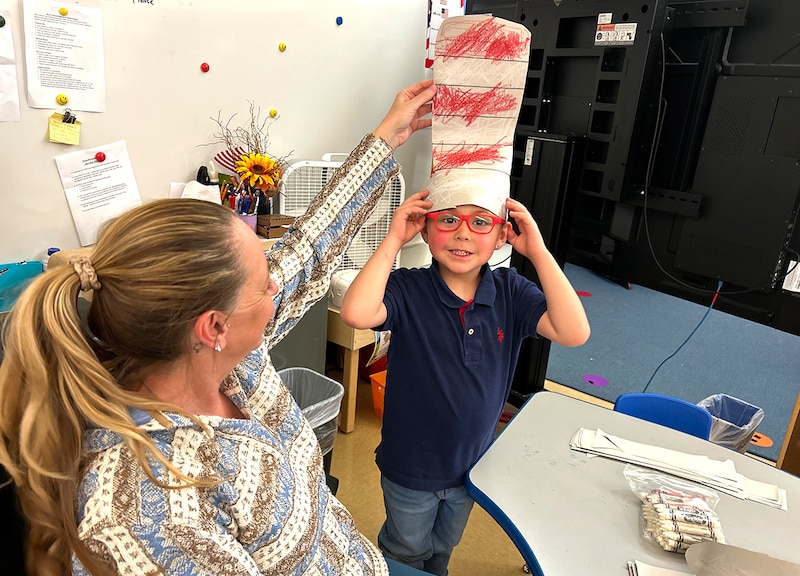 A boy has a red and white striped hat on.