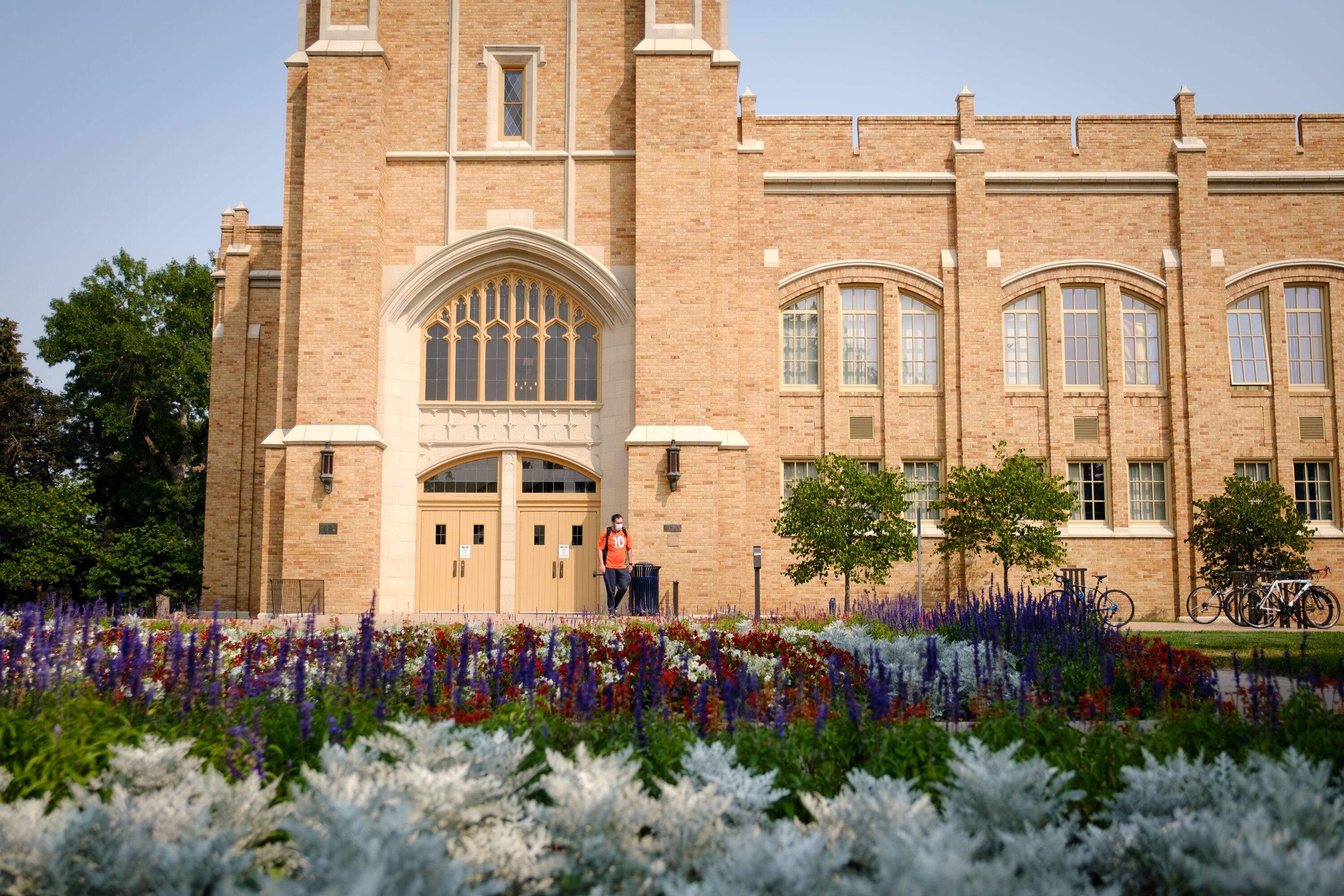 Flowers are planted in front of a brick building.