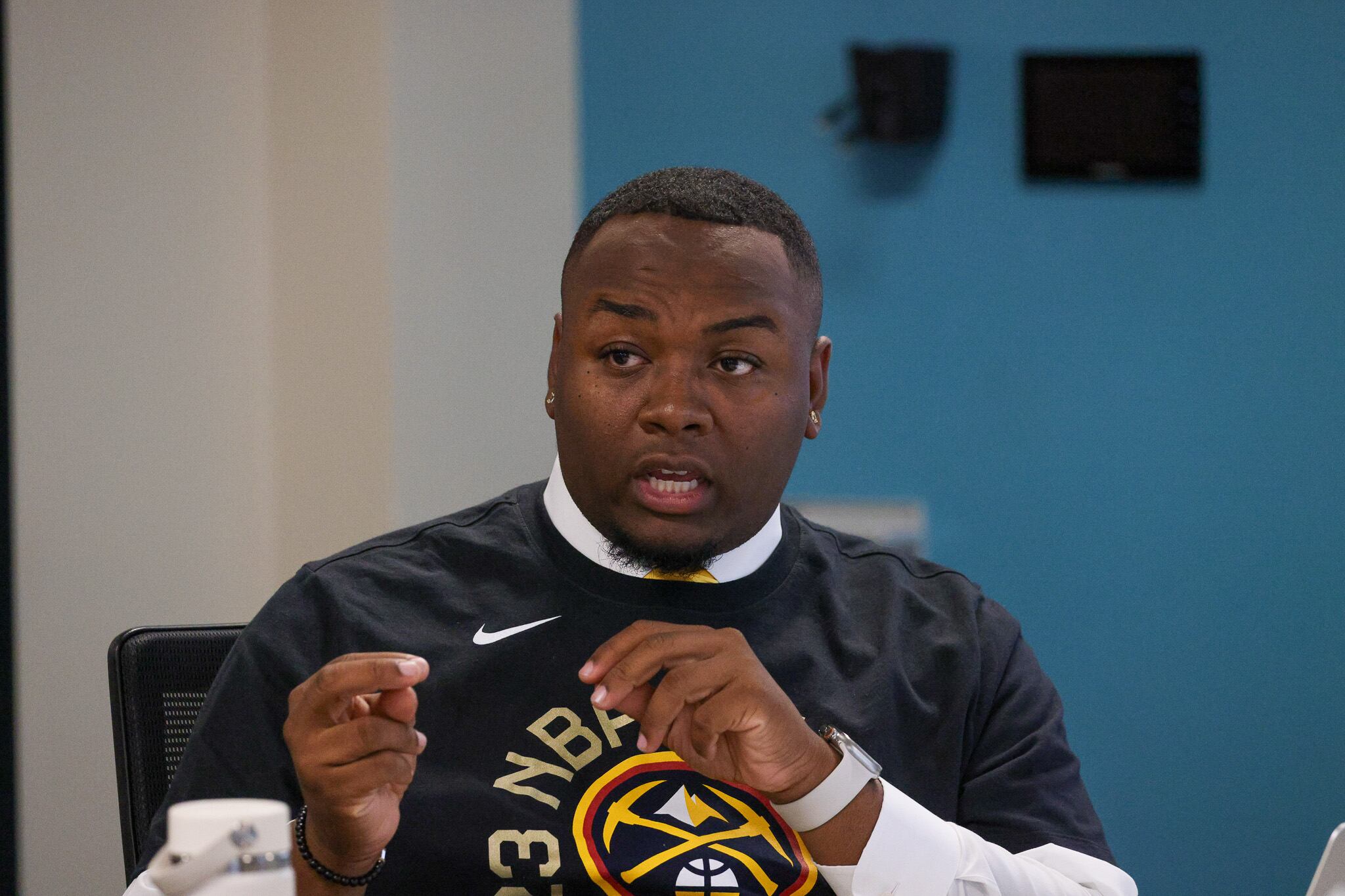 Denver school board Vice President Auon’tai Anderson, in a black Nuggets t-shirt, gestures as he speaks at a school board meeting.