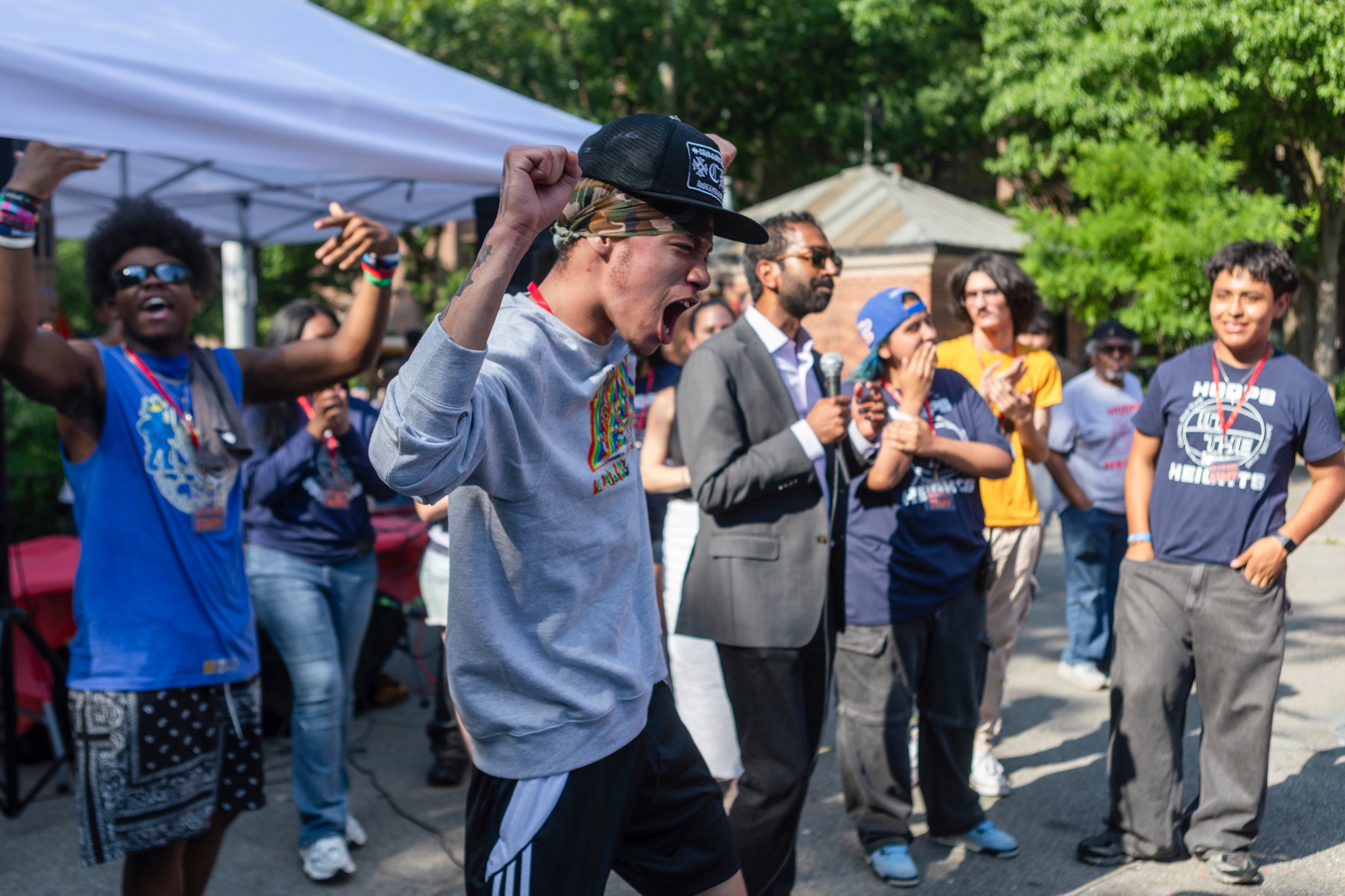 A student with a blue cap celebrates surrounded by other people.