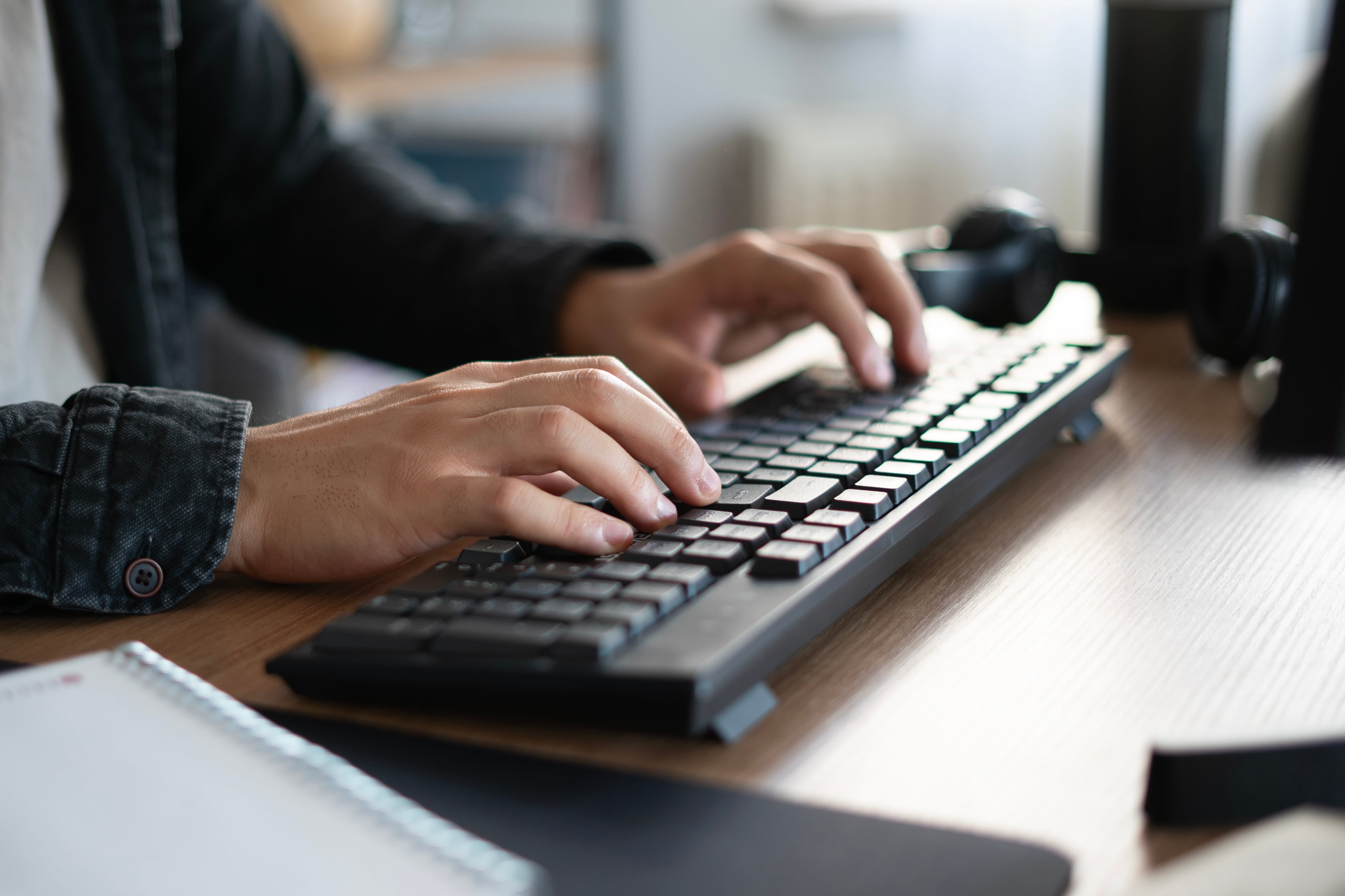 An up close photograph of a pair of hands work on a computer keyboard.