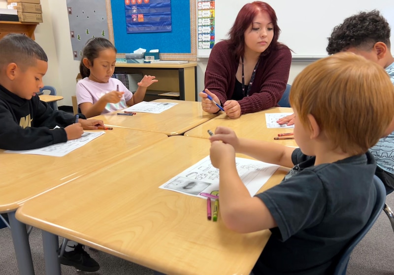 A photograph of a dry erase board and a poster with words and drawings in a classroom.